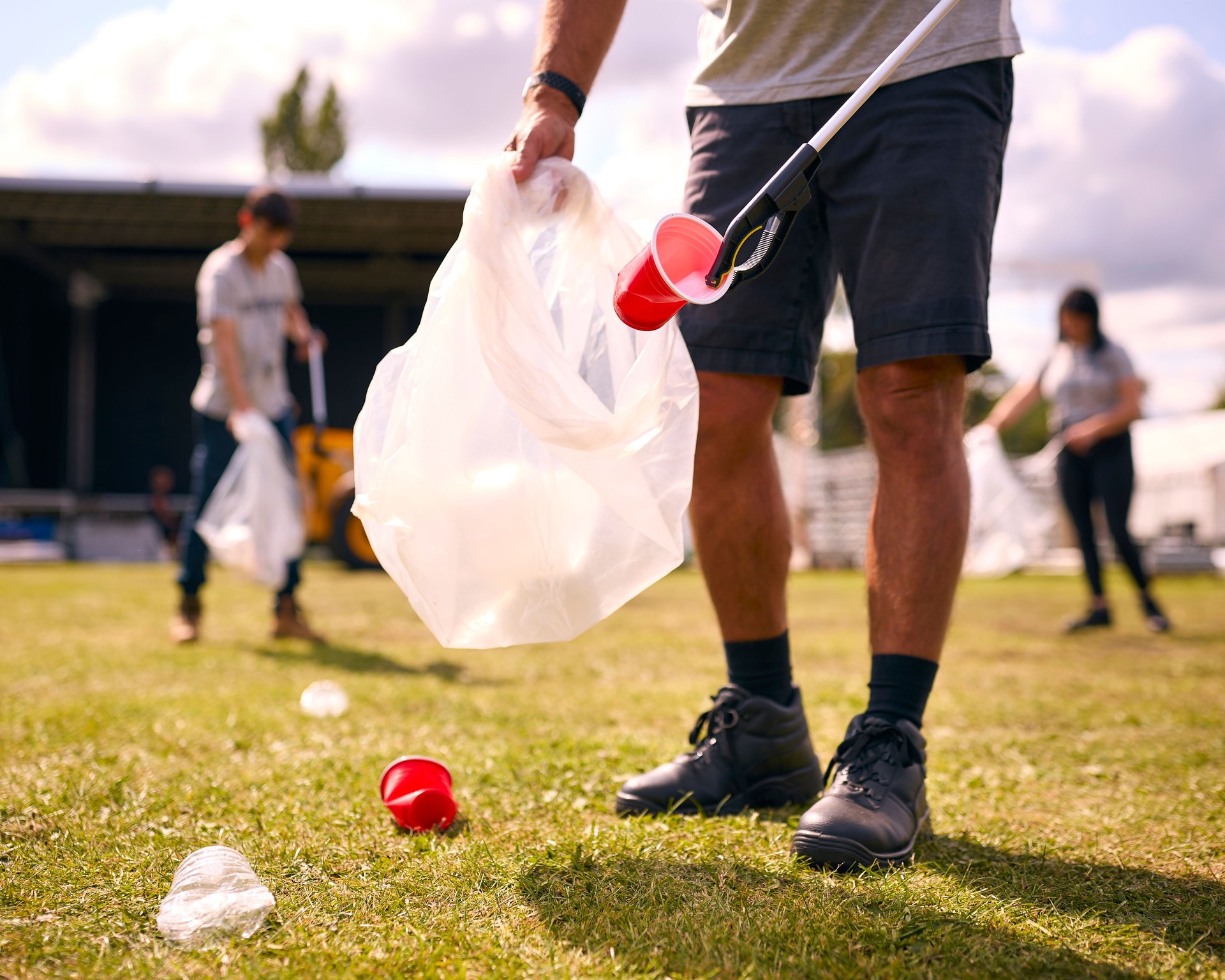 Close Up Of Volunteers Picking Up Litter After Outdoor Event Like Concert Or Music Festival